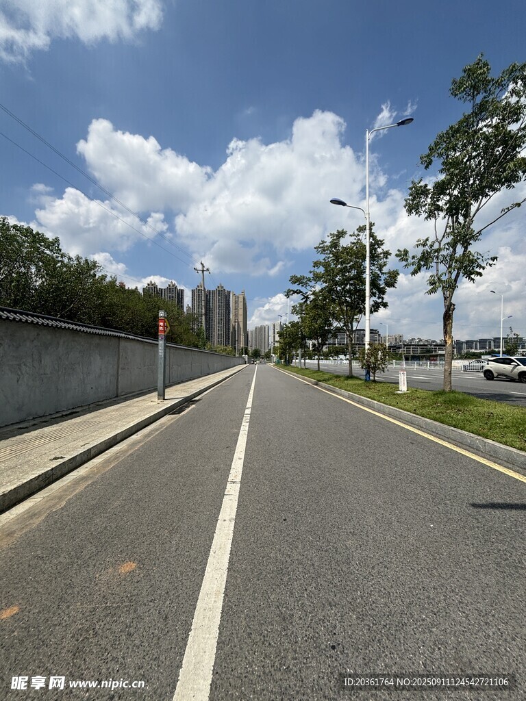 宽阔道路旁绿树蓝天白云