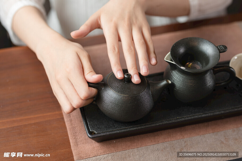 双手抚弄古朴茶具