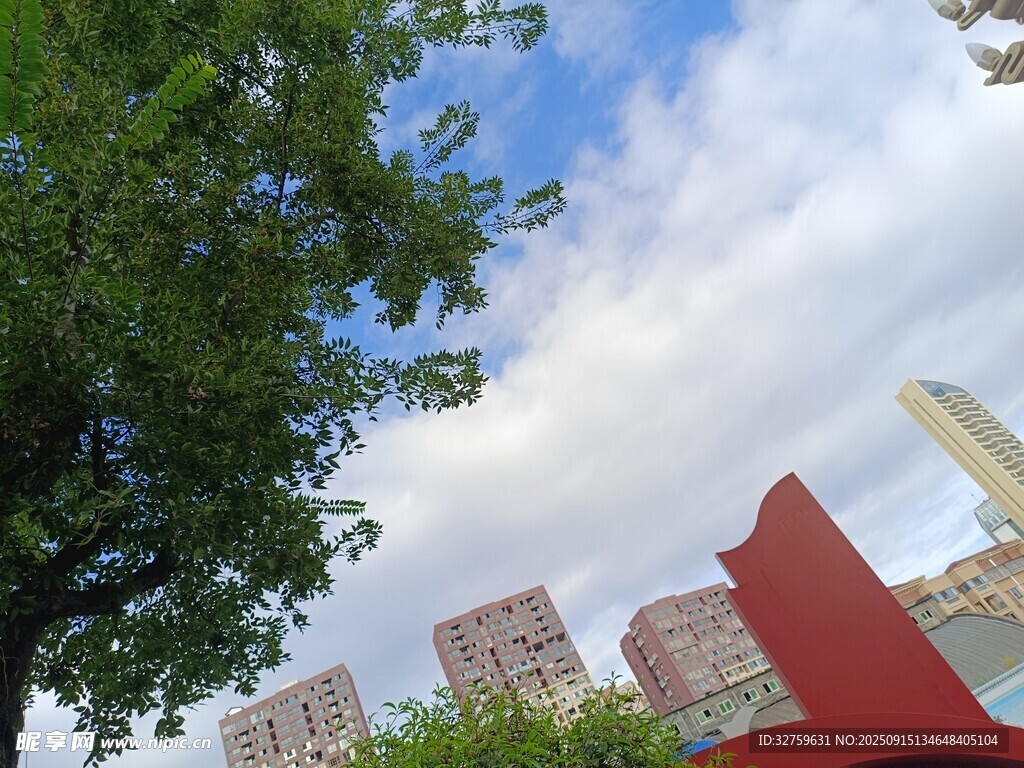 城市绿树旁的红色雕塑