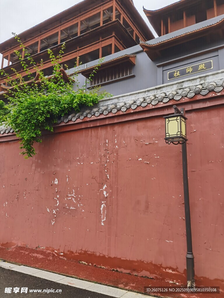 红墙古建筑旁的绿植与路灯