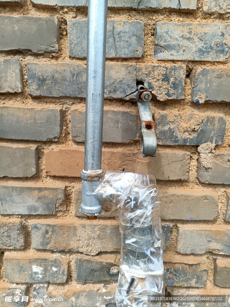 砖墙旁的金属管道与包裹物