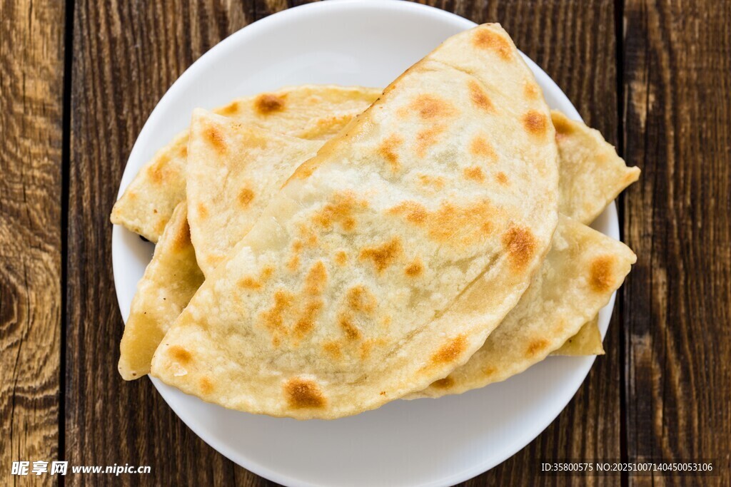 木桌上白盘里的美味烙饼