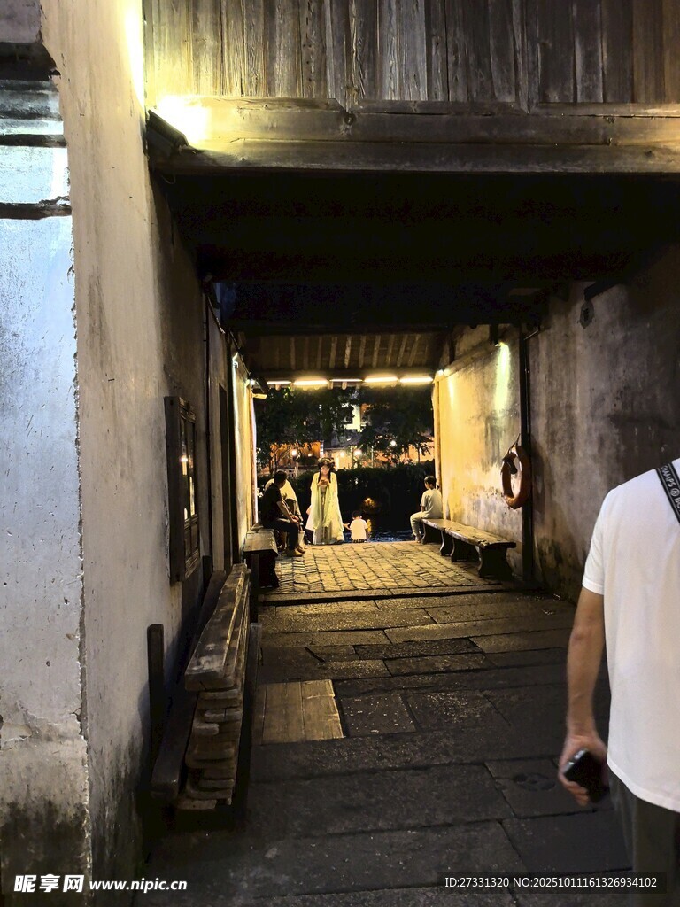 古巷夜景中的行人身影