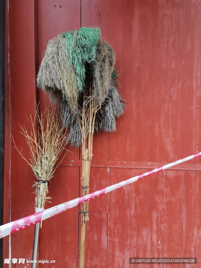 老旧扫帚靠在红墙边