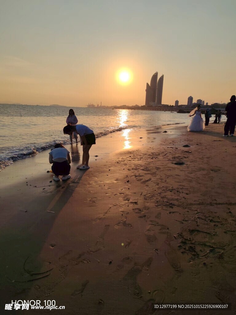 夕阳下的海边漫步人群