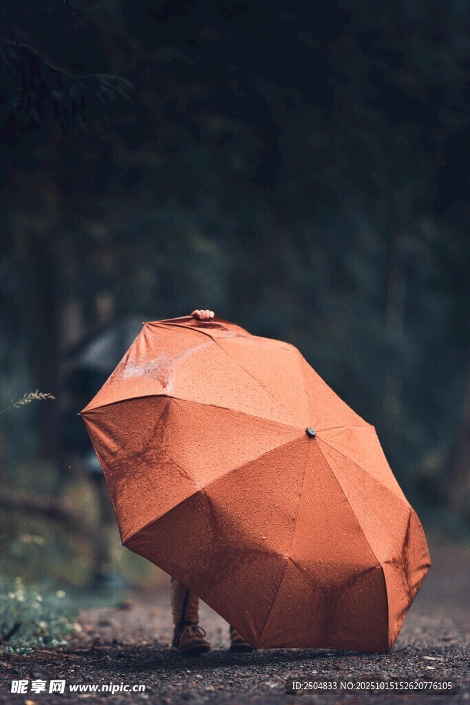 雨中橙色雨伞下的孤独身影