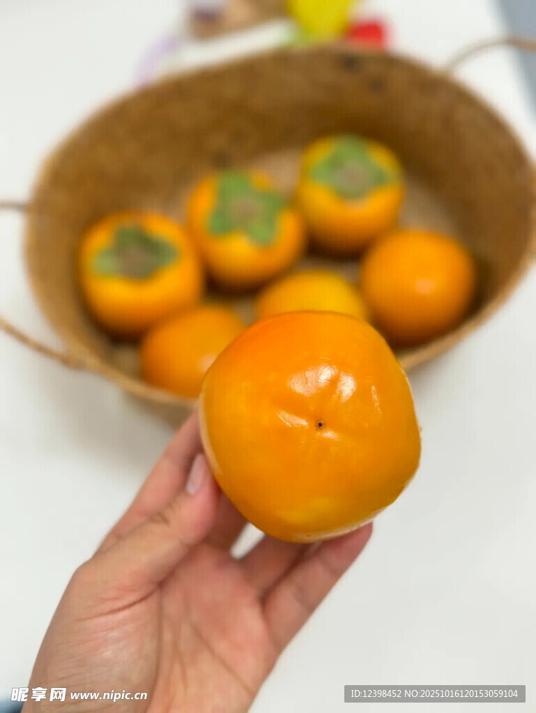 手捧鲜橙与筐中柿子