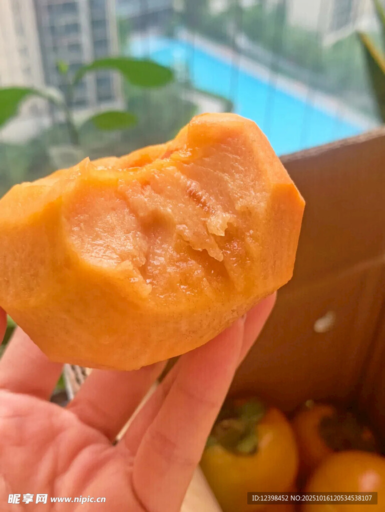 手拿咬过的香甜黄柿子