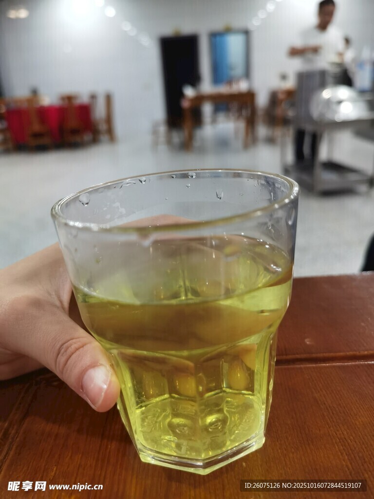 手持玻璃杯中的黄色饮品