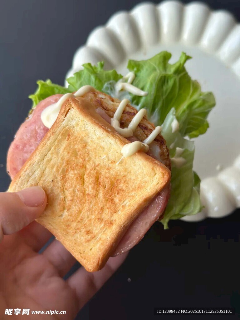 手持美味生菜火腿三明治