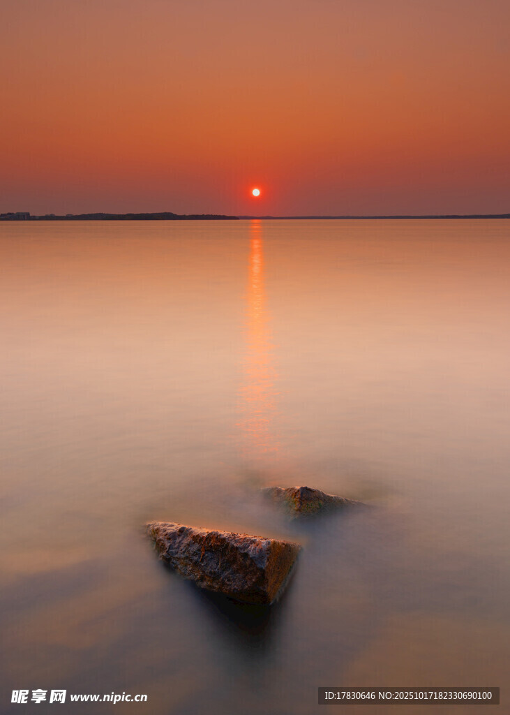 夕阳下静谧湖面的孤石