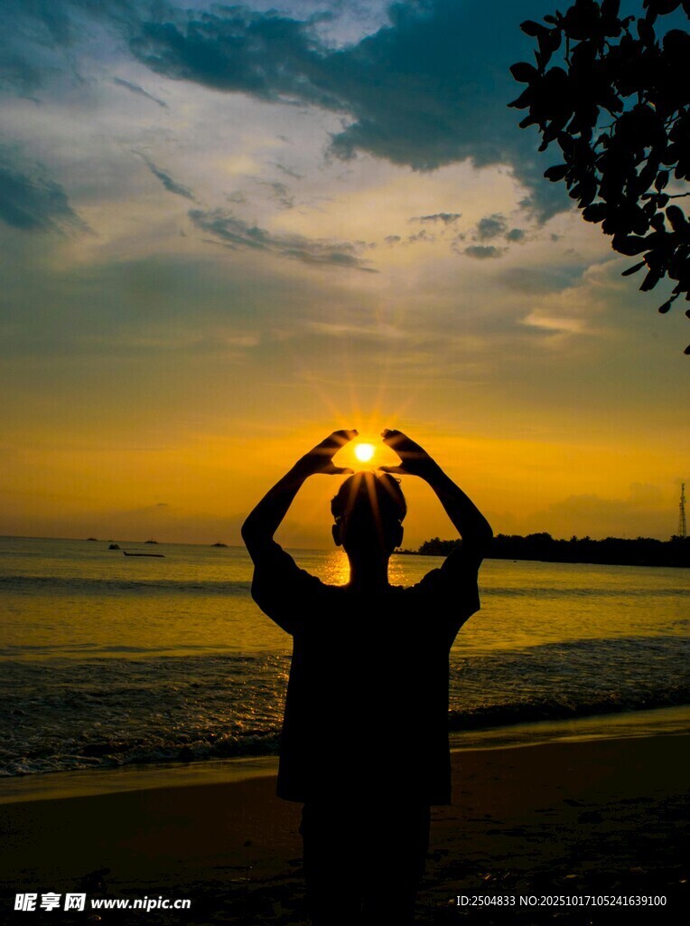 夕阳下海边比心的剪影