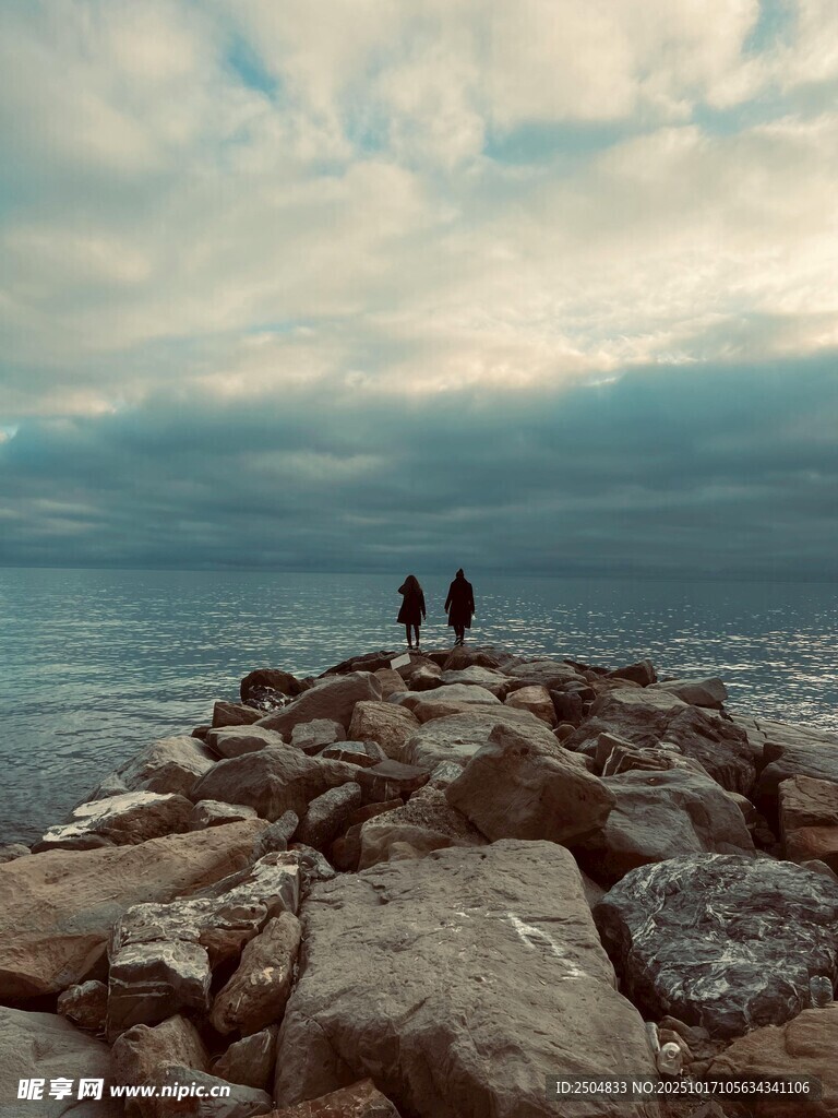 海边岩石上的三人身影