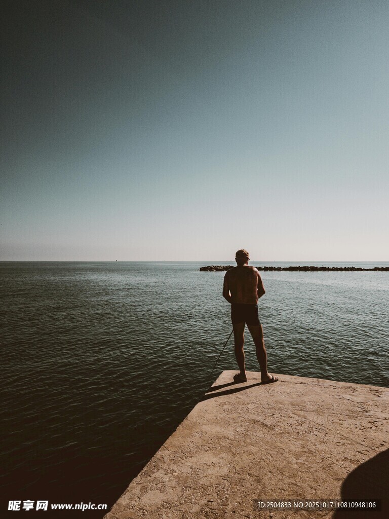 一人伫立海边岩石远眺