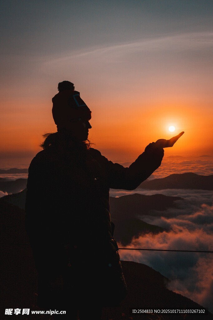 伸手迎朝阳的登山者