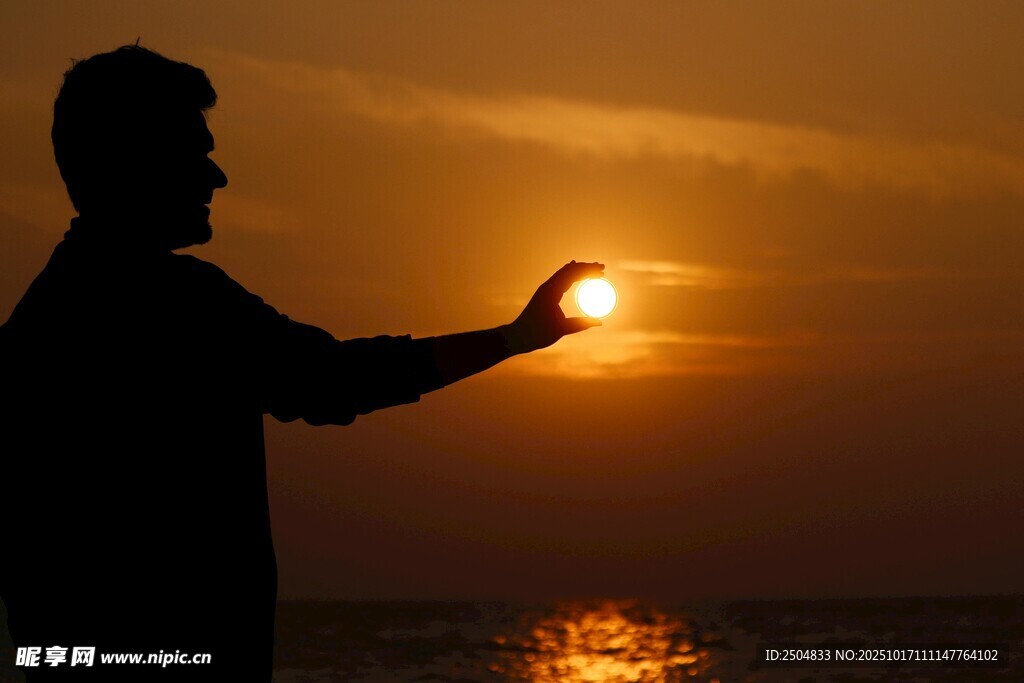 夕阳下男子伸手托举落日
