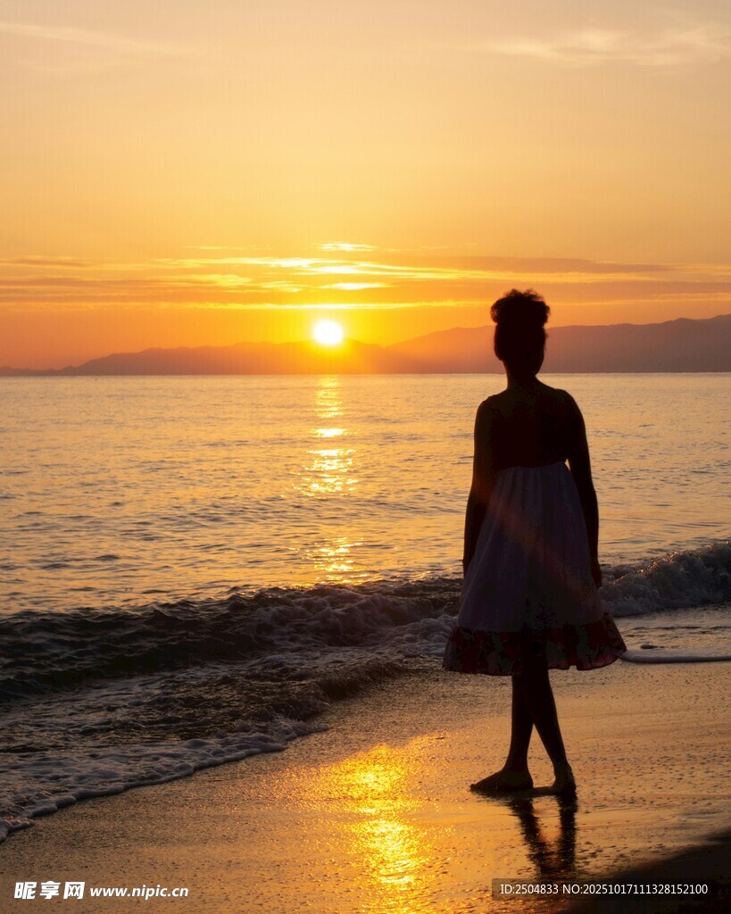 夕阳下海边漫步的女子
