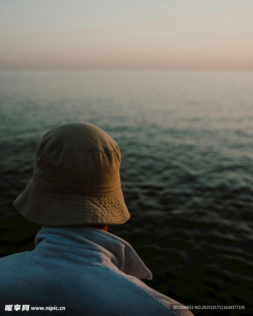 海边戴帽者的静谧背影