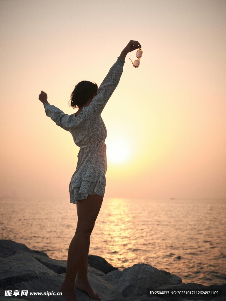 海边女子迎日落舒展身姿