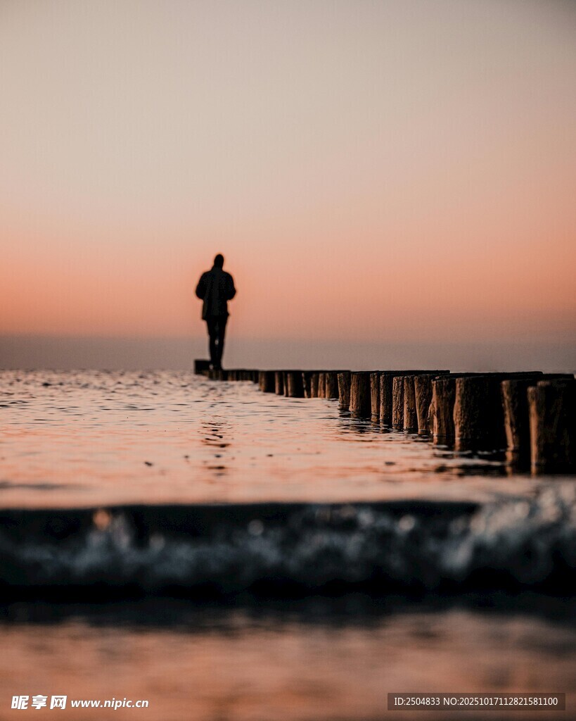夕阳下海边栈桥上的身影