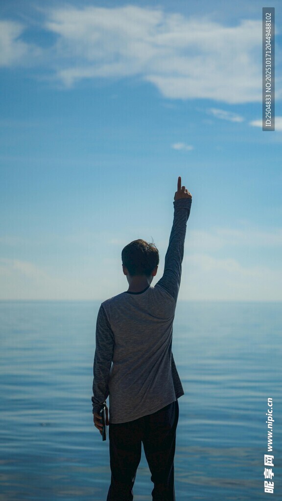 男子海边高举手臂望天空
