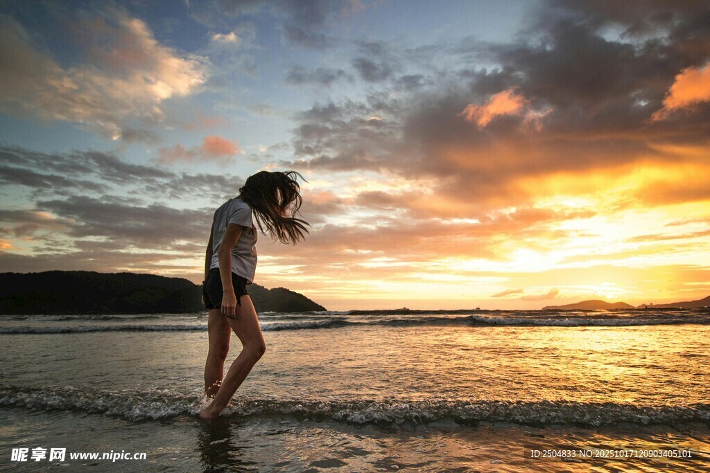 夕阳下海边漫步的女子