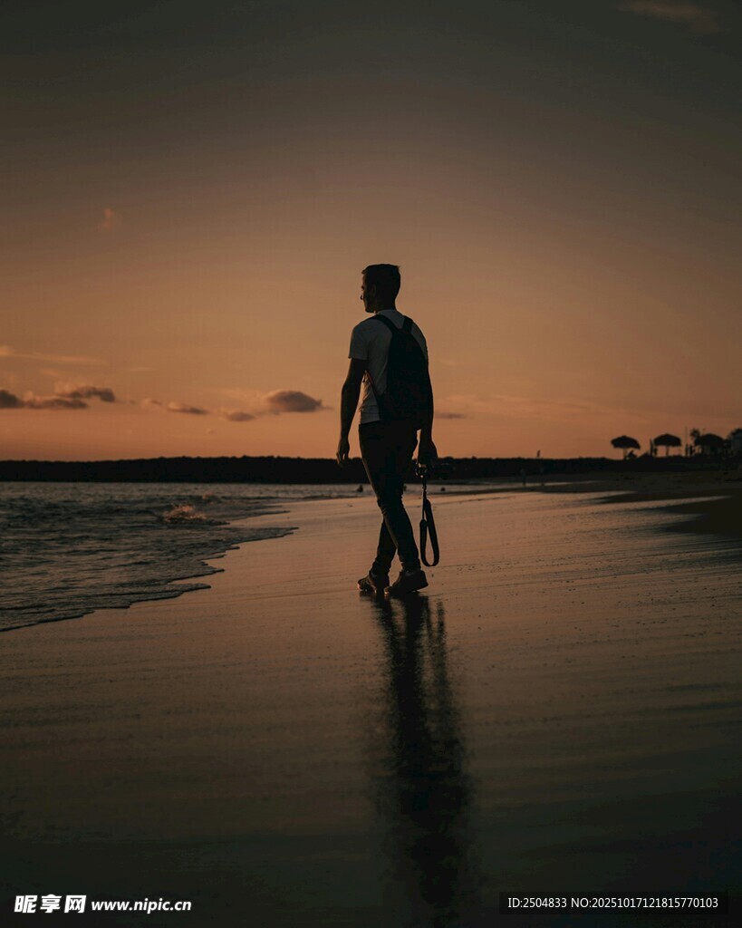 夕阳下海边独自行走的人
