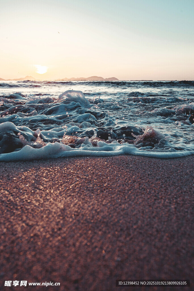 夕阳下的海浪拍打沙滩