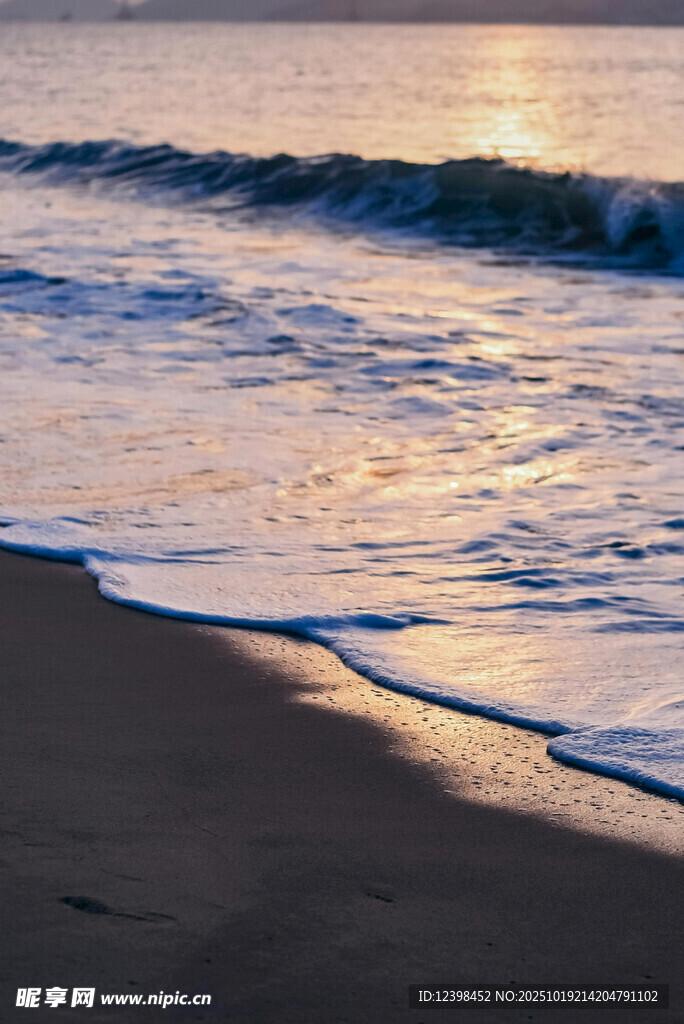 夕阳下的海浪轻拍沙滩