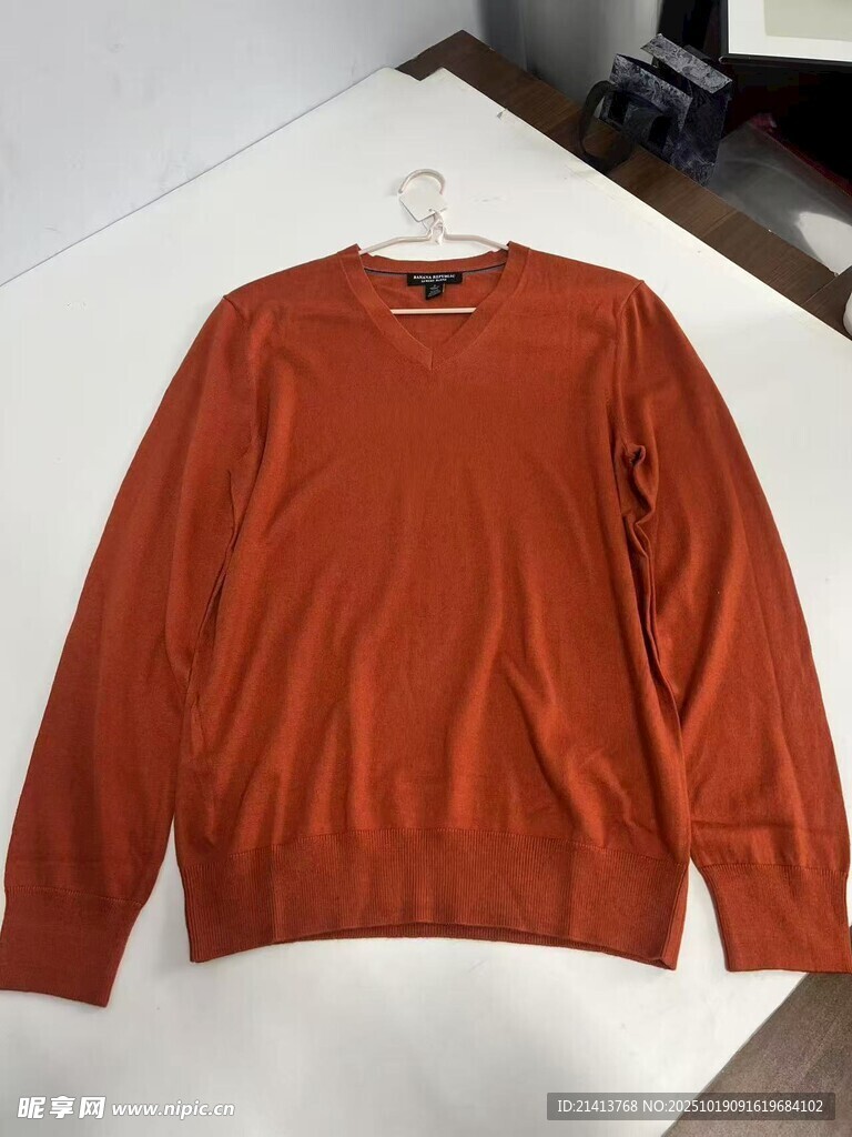 橙色长袖毛衣挂于衣架