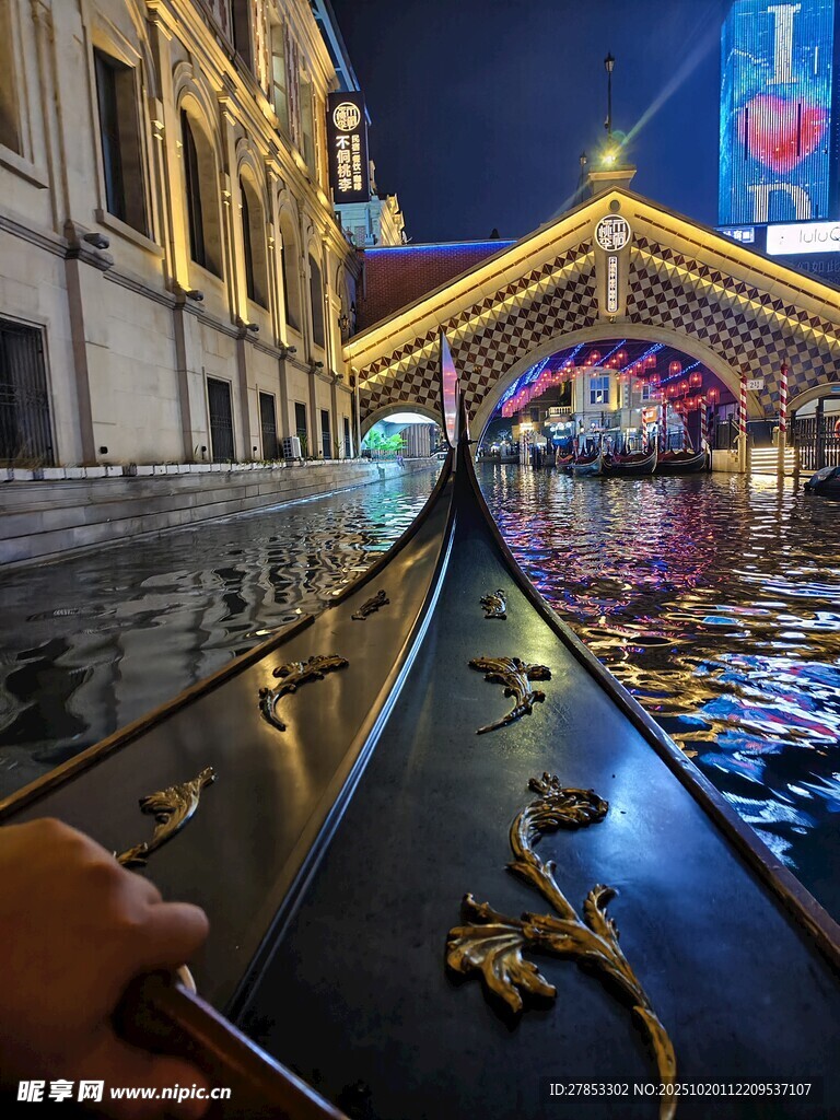 夜晚河畔璀璨灯光下的小船