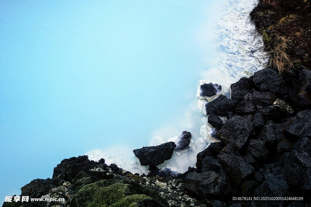 蓝色水域旁的黑色岩石景观