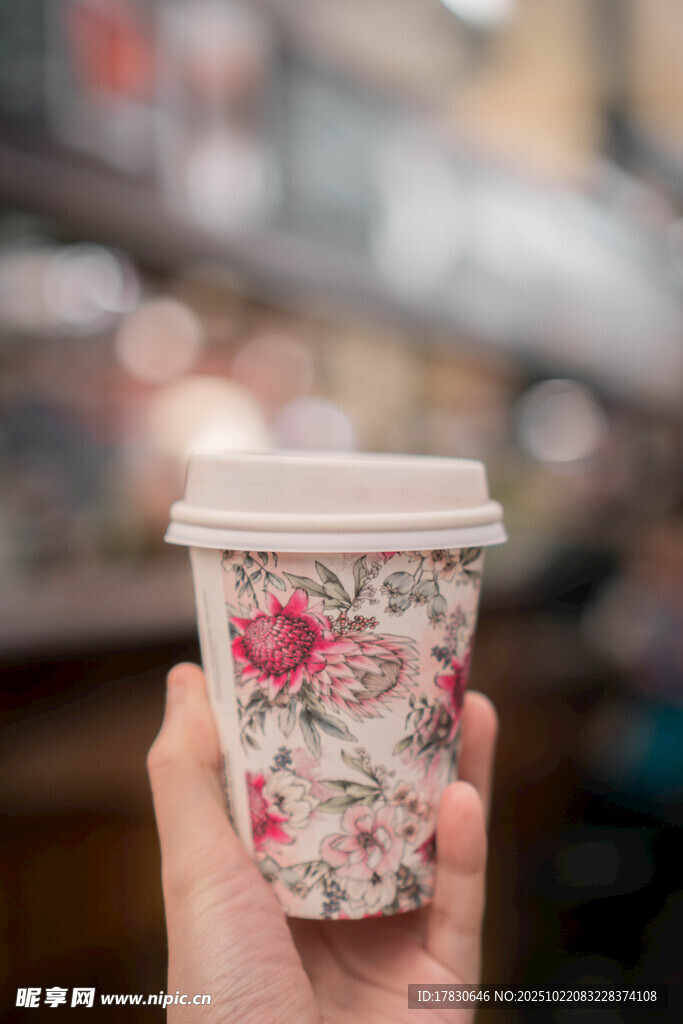 手持花卉图案咖啡杯