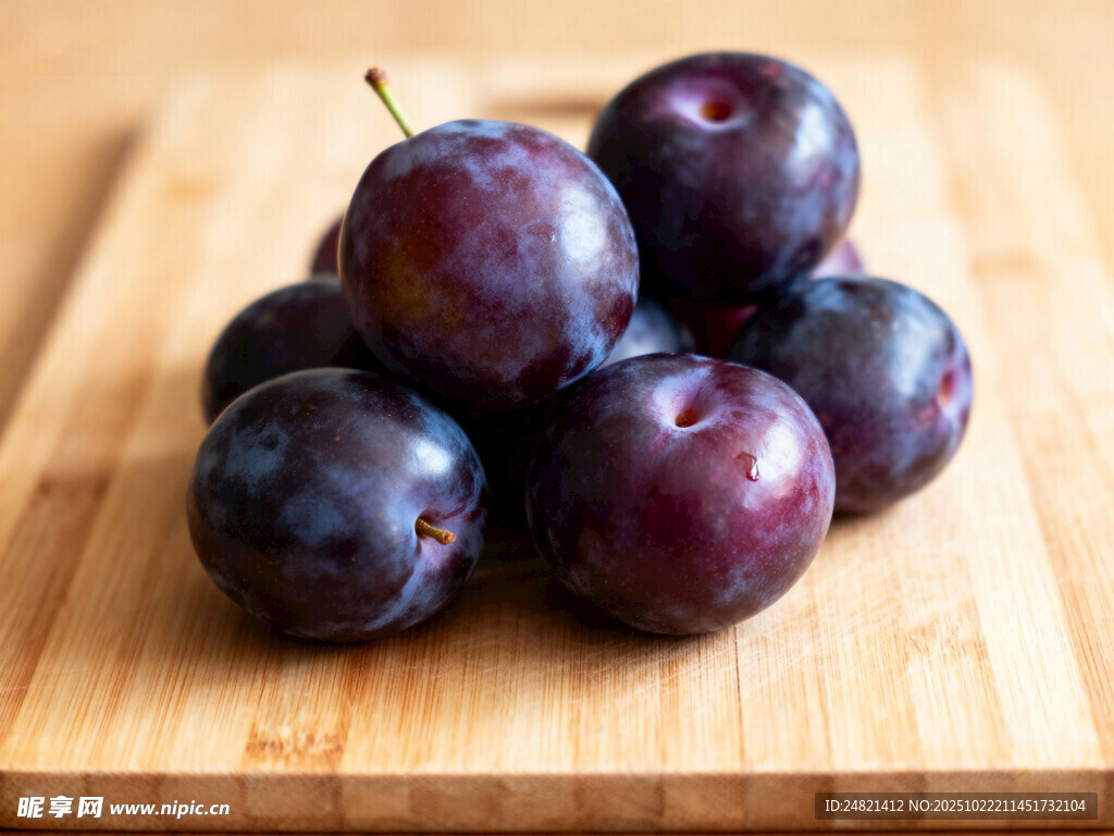 紫黑色李子摆放在木砧板上