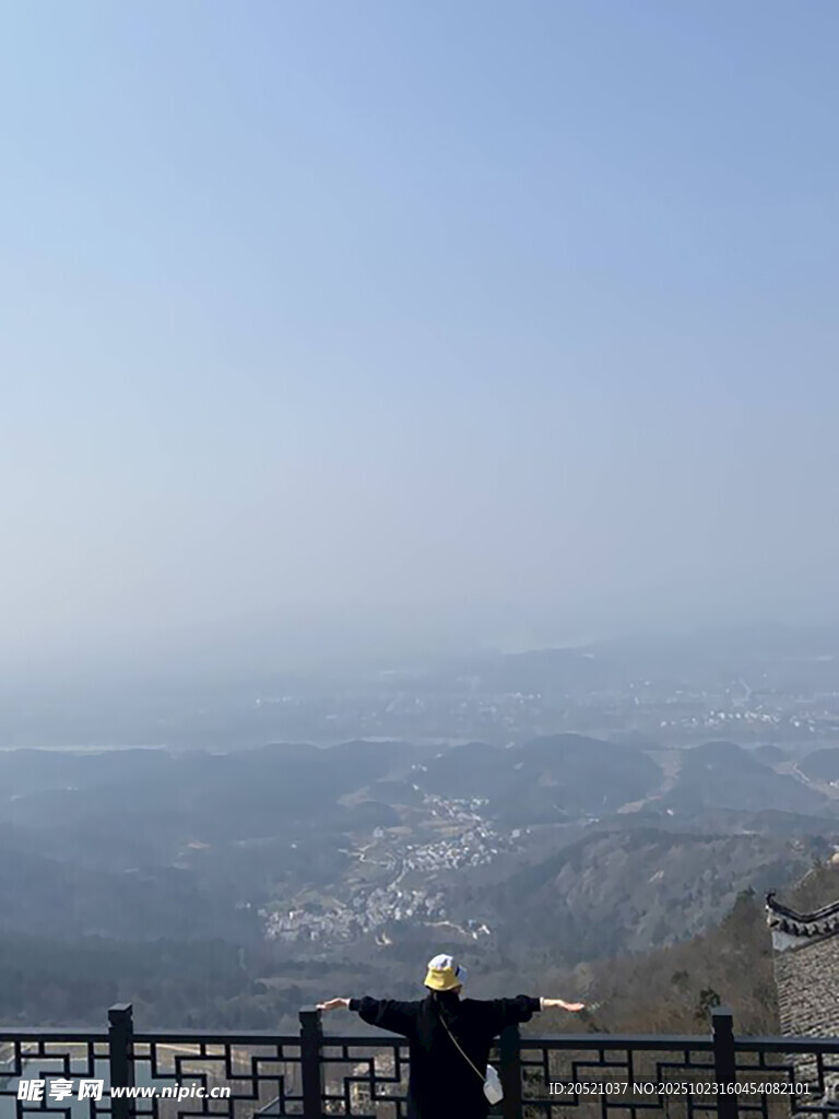 山顶游客展臂赏辽阔风景