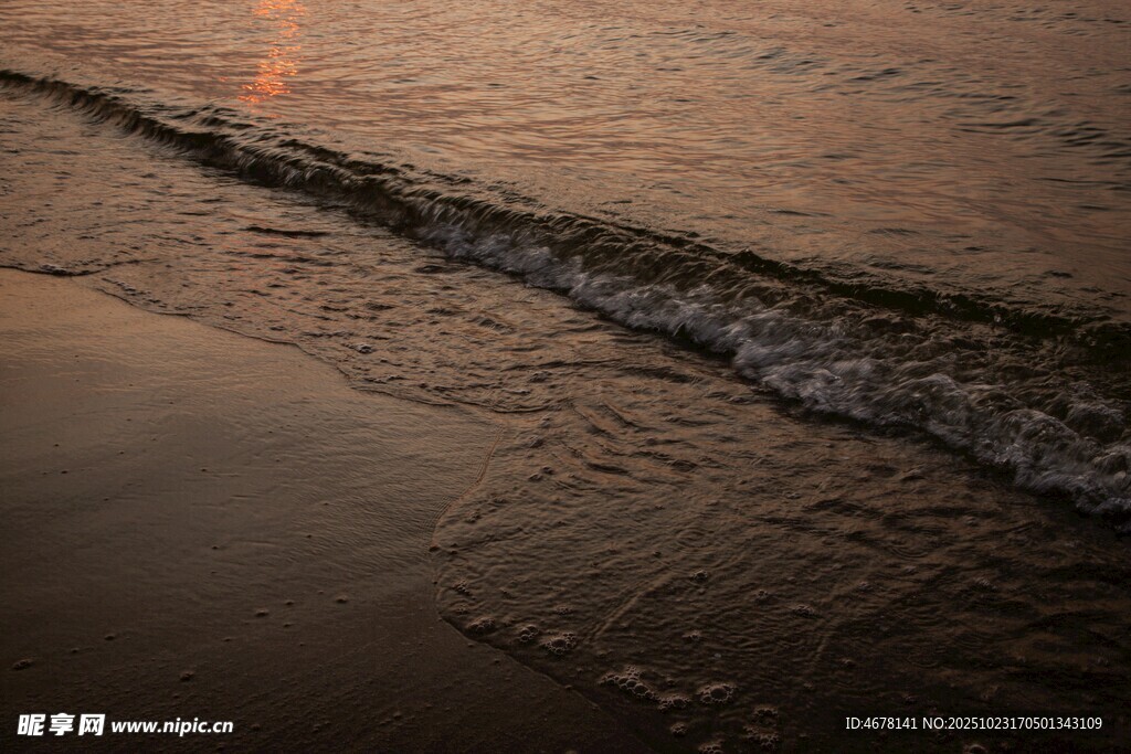 夕阳下的海浪轻拍沙滩