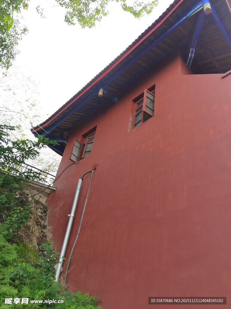 红墙建筑旁的葱郁绿植