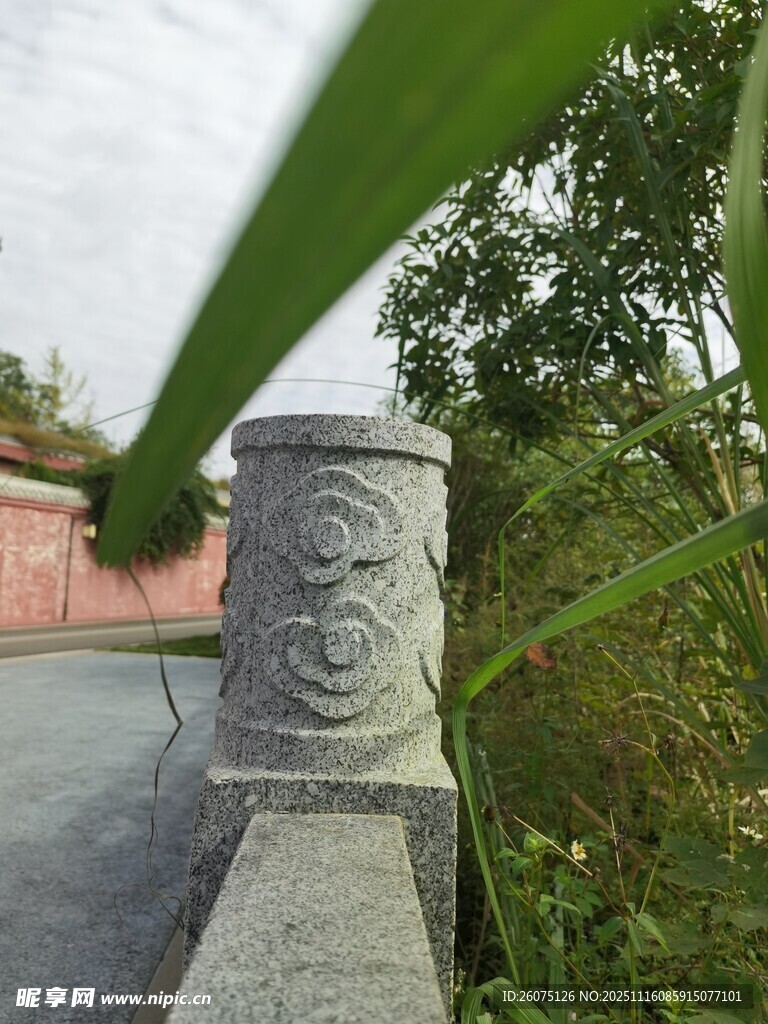 石雕柱旁的绿植与建筑