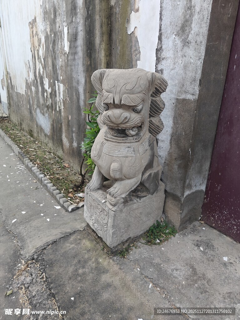 古老石狮子立于墙边