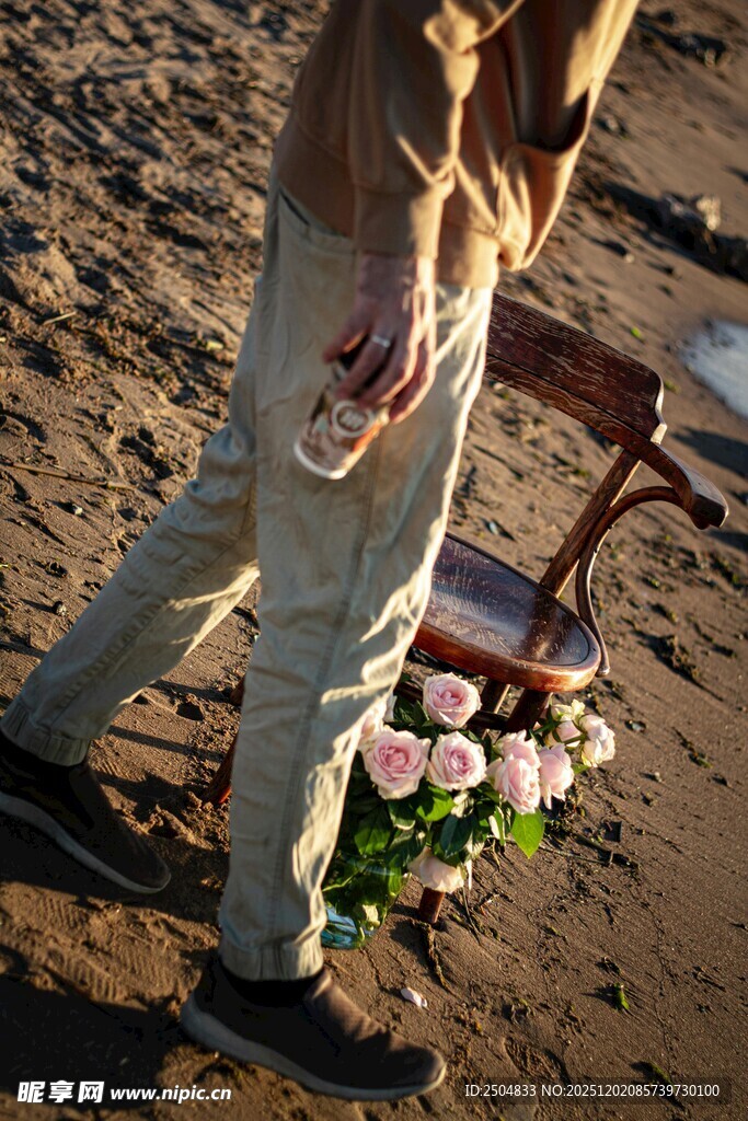 男子手持花束于沙滩上