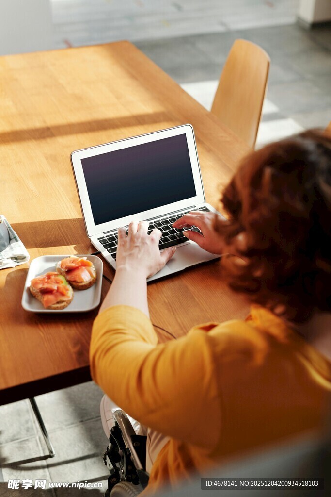 女子桌边用笔记本电脑用餐