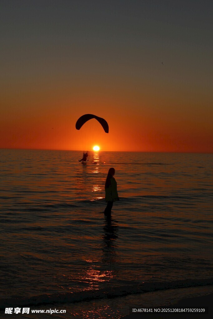 夕阳下的海边滑翔伞运动
