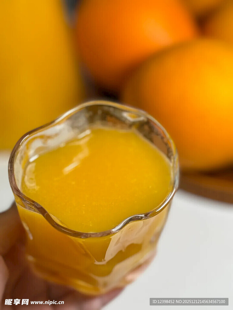 手持玻璃杯中的鲜榨橙汁