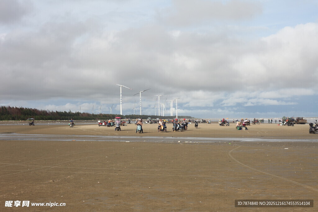 海滩上的人群与远处帆船