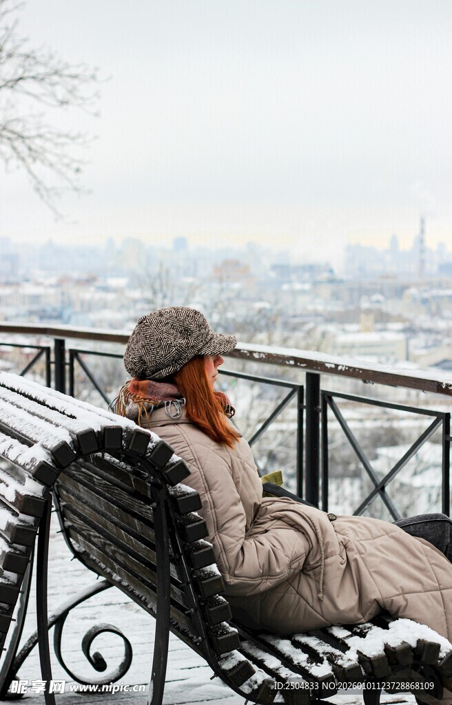 冬日长椅上远眺城市的女子