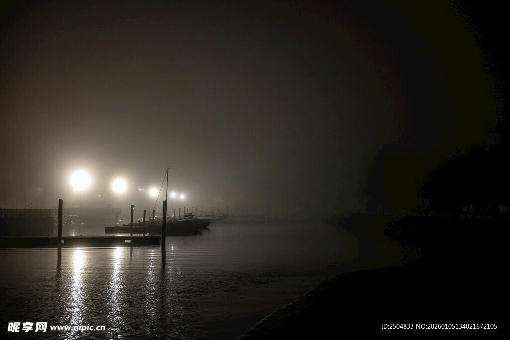 雾中灯光映照水面夜景