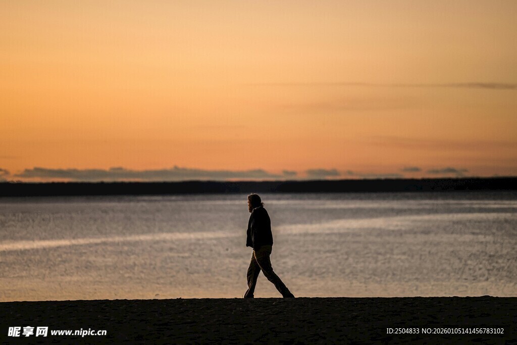 夕阳下海边独自行走的人