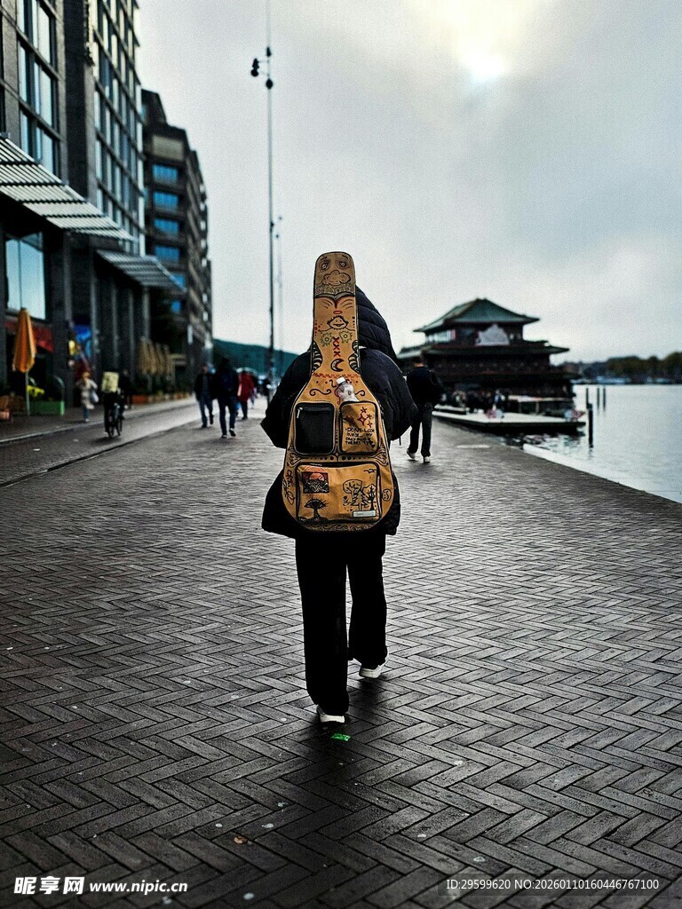 女孩背吉他漫步滨水步道