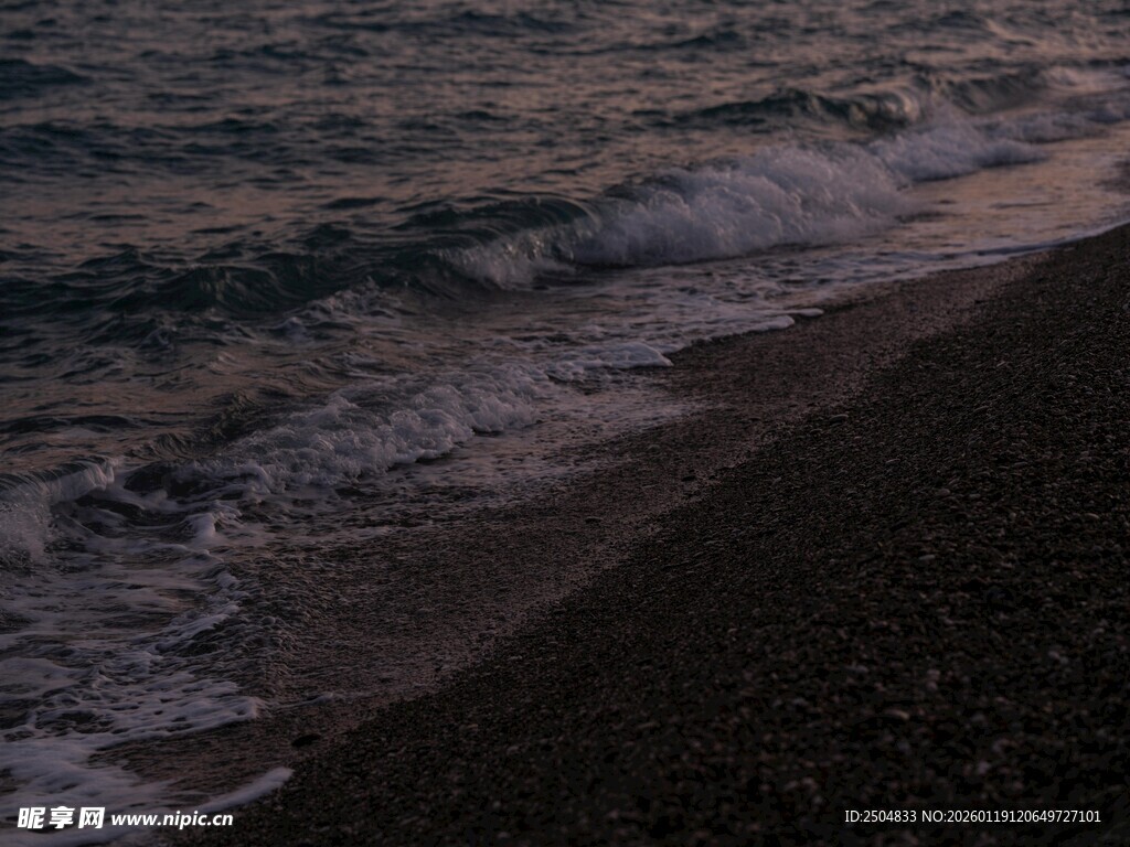 黄昏下的海浪拍打黑色沙滩