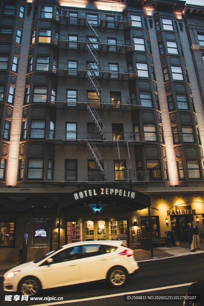 夜晚街边的高楼与白色轿车